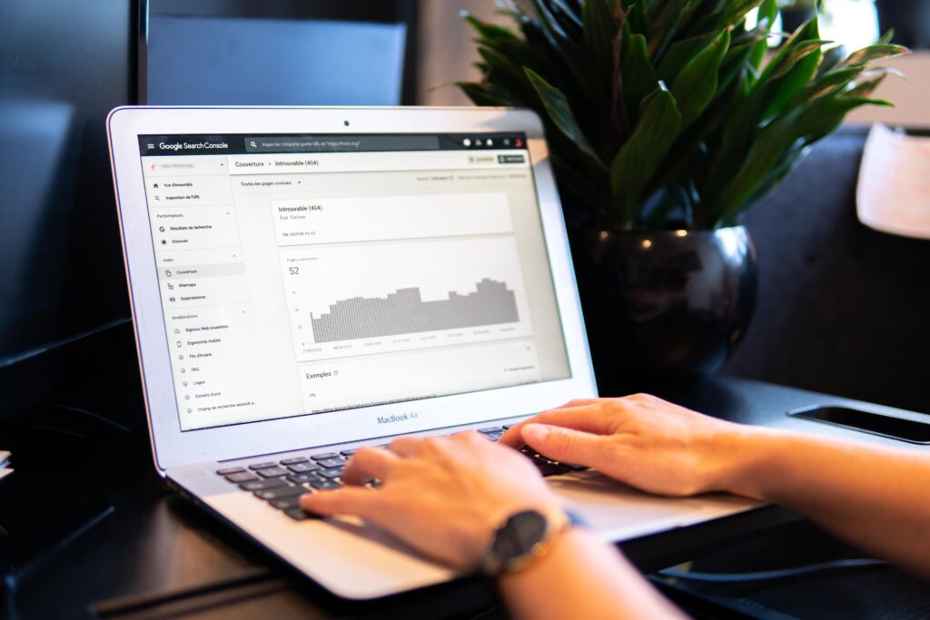 a person’s hands typing on a macbook on a brown table