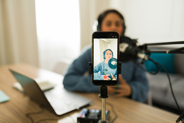 Female podcaster recording audio and live streaming content using smartphone