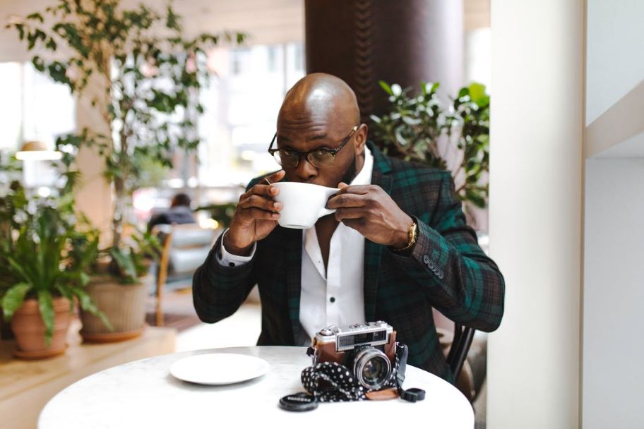 man-sitting-in-front-of-round-table-while-sipping-from-white-ceramic-mug