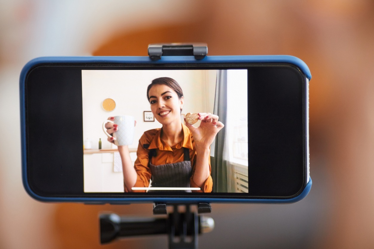 Close up of smartphone screen with smiling woman recording cooking tutorial for video channel, copy space