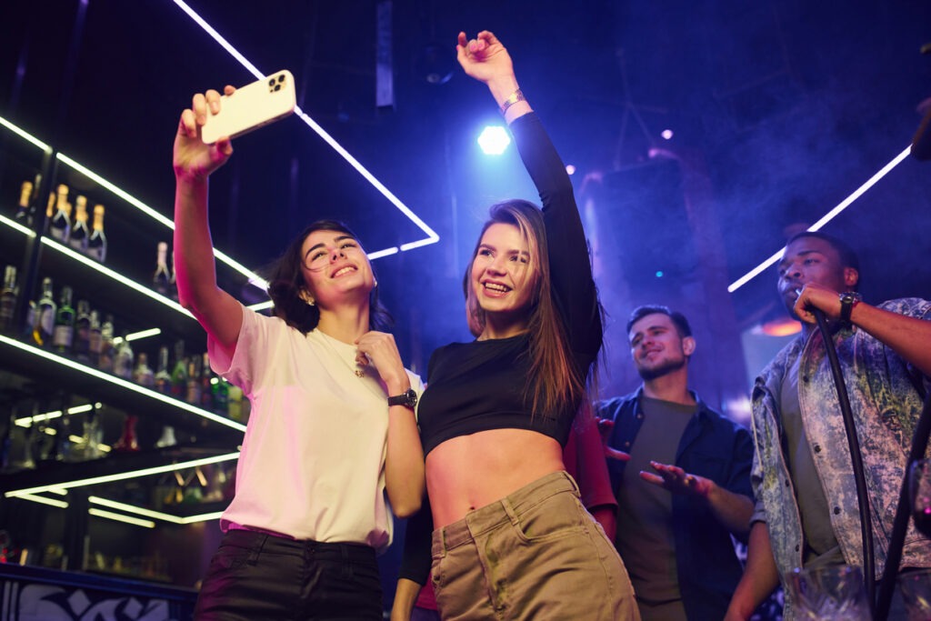 Two women making selfie. Group of friends having fun in the night club together