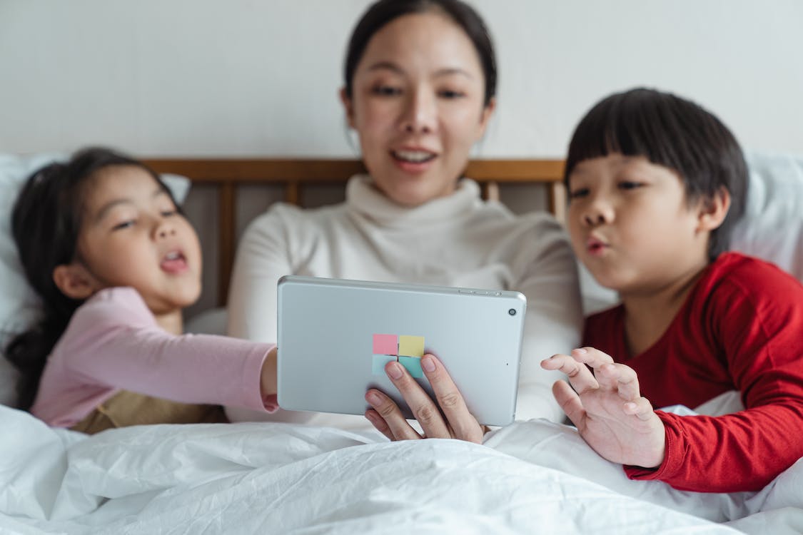 happy ethnic mother and children choosing content on tablet